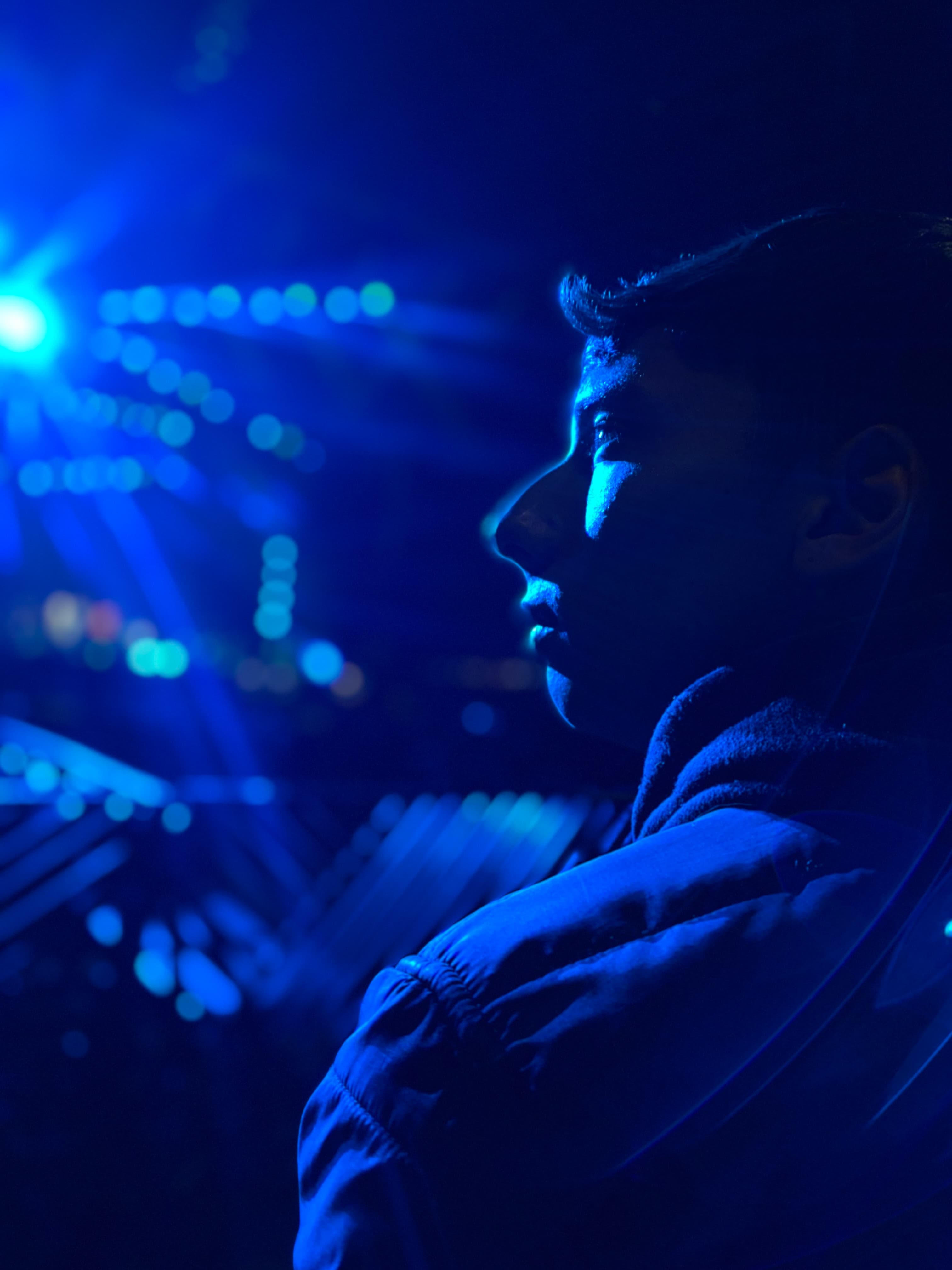 Blue-lit profile of ANDY EMBER in a stage environment