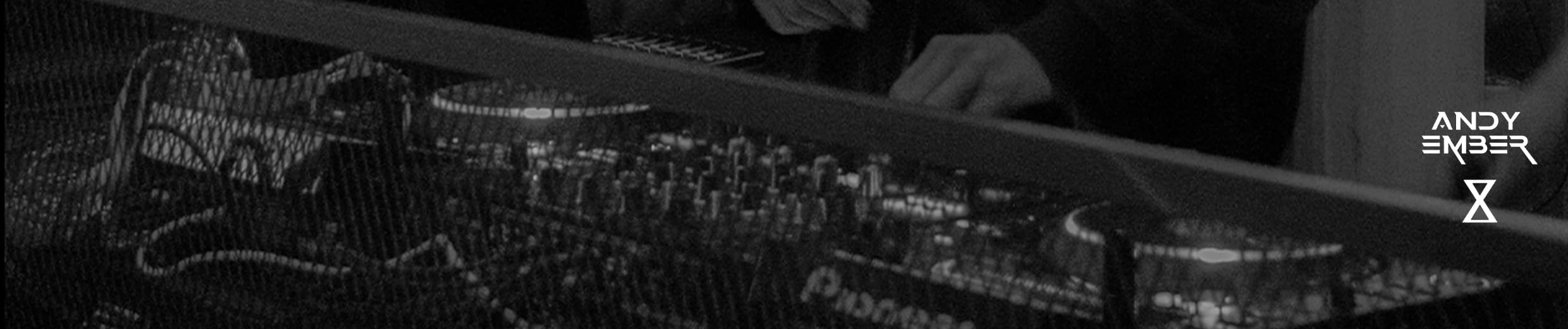 Wide black and white banner of ANDY EMBER at DJ decks