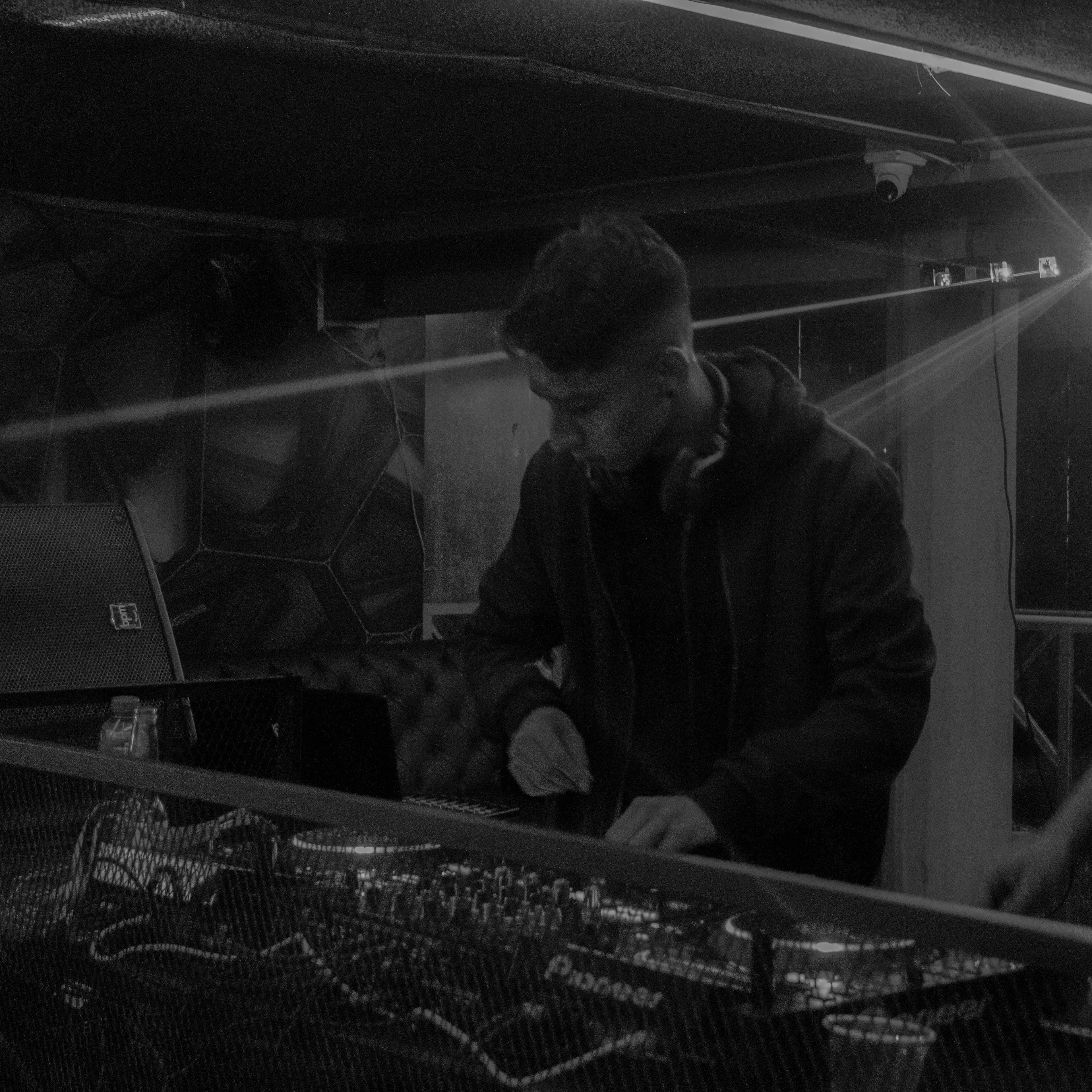 ANDY EMBER performing behind DJ decks in black and white